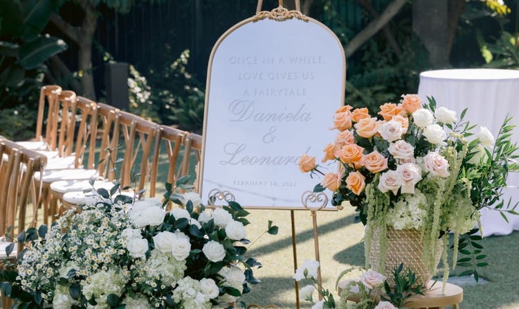A wedding welcome sign flanked by floral arrangements