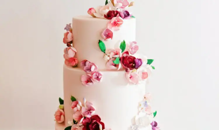 A 4 tier wedding cake covered in cascading sugar flowers