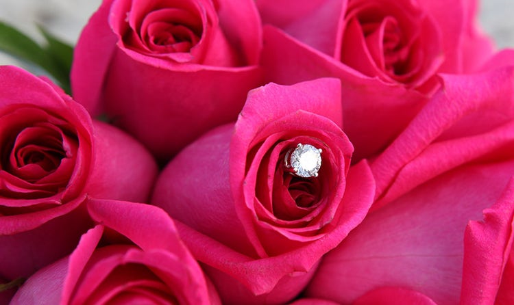 A diamond shaped charm in the middle of a bouquet of roses