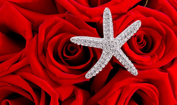 A starfish charm sitting on a bed of roses