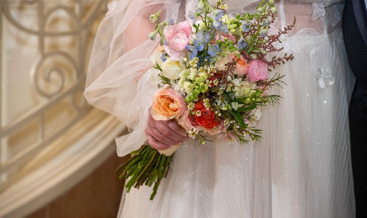 A bride holding a bouquet with peonies, rosemary and amaranth