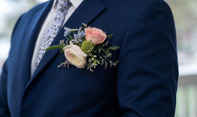 A groom wearing a boutonniere with 2 roses