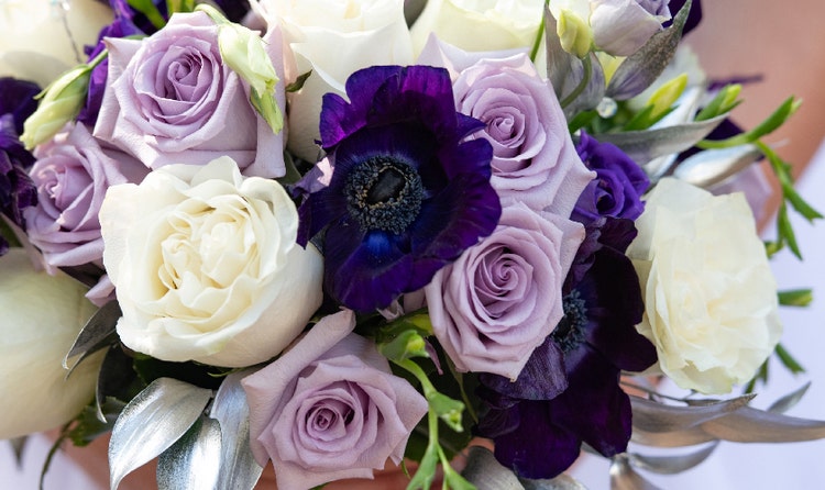A bride holding a bouquet with roses and anemones
