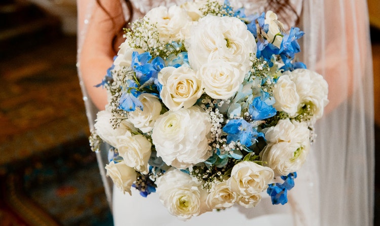 A bride holding a bouquet with roses, delphiniums and peonies