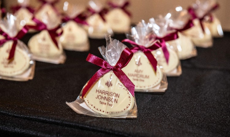 Individually wrapped wedding favors tied with ribbons featuring tags with Guest names and table assignments