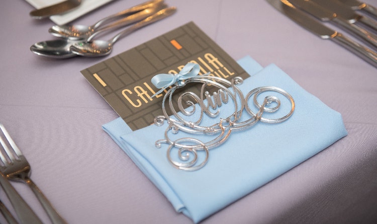 Place setting featuring a folded napkin, flatware, a scroll name tag and a menu card labeled 'California Grill’