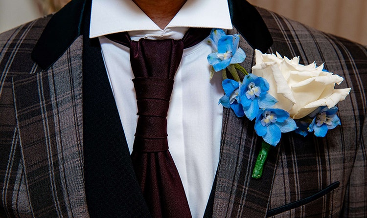 A groom wearing a boutonniere with a rose and other flowers
