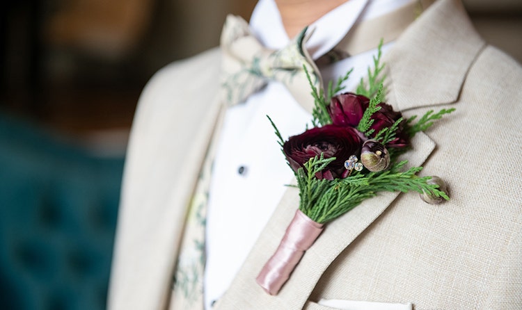 A groom wearing a boutonniere with a mix of flowers