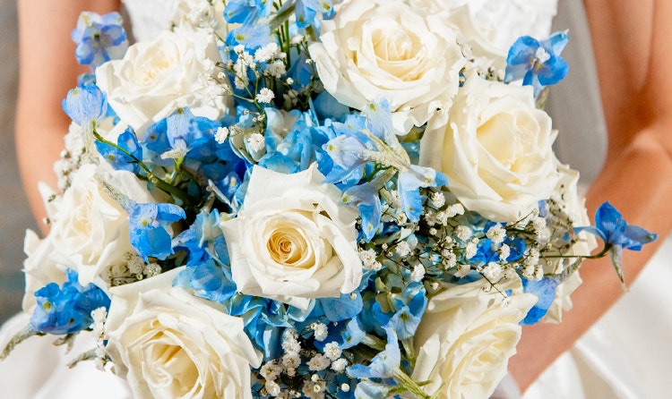 A bride holding a bouquet with roses and delphiniums