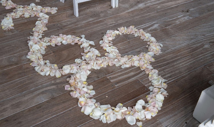 Flower petals arranged in the shape of Mickey Mouse on a wooden deck