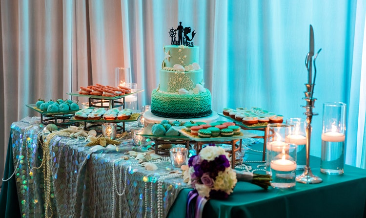 Wedding cake on table with candles, pastries and beads