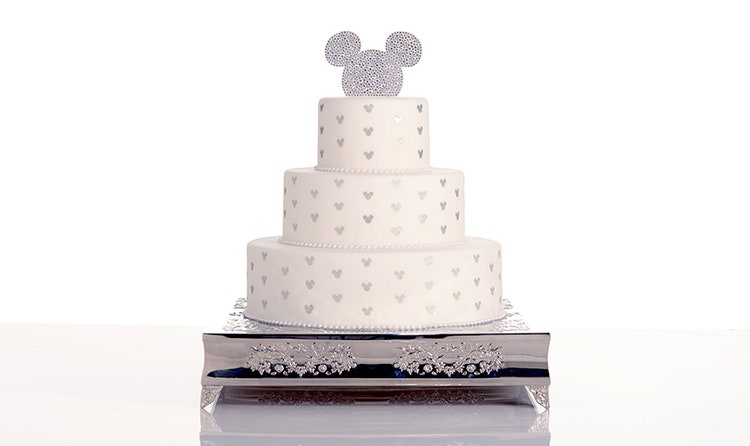 A 3 tier wedding cake topped with a shape of Mickey Mouse
