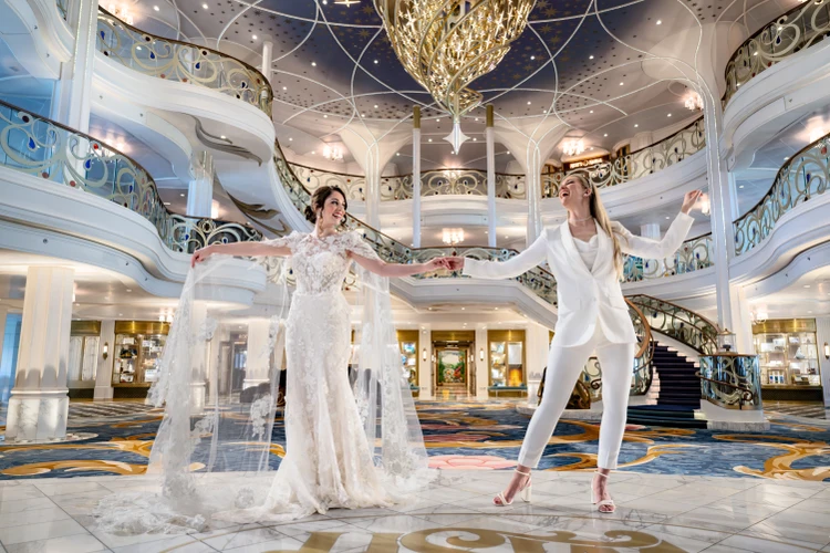 Two brides dancing on the stage of the Grand Hall on the Disney Wish