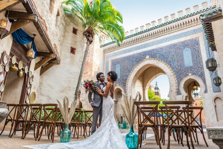A bride and groom stand amid empty chairs and gaze into each other’s eyes in the EPCOT Morocco Pavilion at Walt Disney World Resort